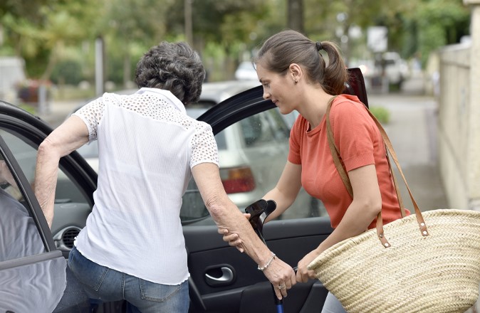 Wat doet een mantelzorger? Deze mantelzorger helpt een mevrouw in de auto te stappen